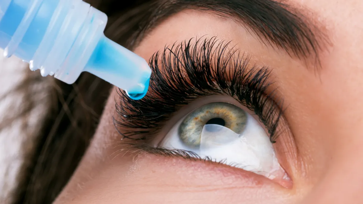 Photo of a woman taking eye drops.