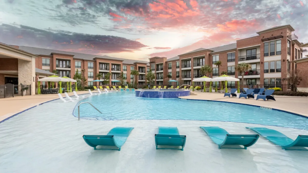 Three-story brick apartments with a pool in the foreground.