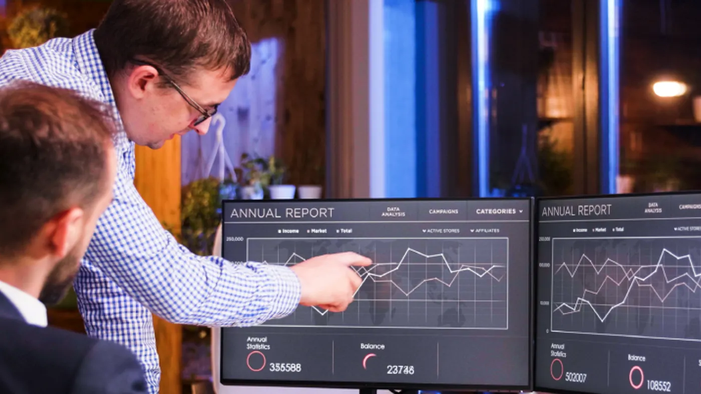 Man pointing at data on a computer monitor