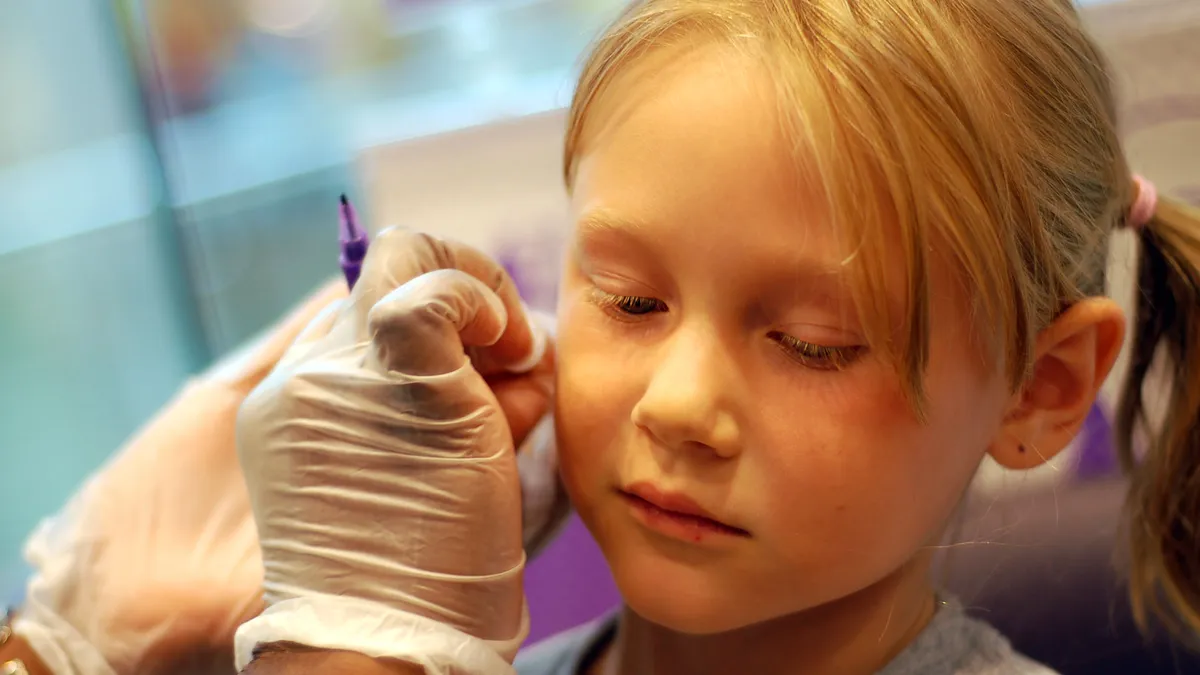 A young girl gets her ears pierced.