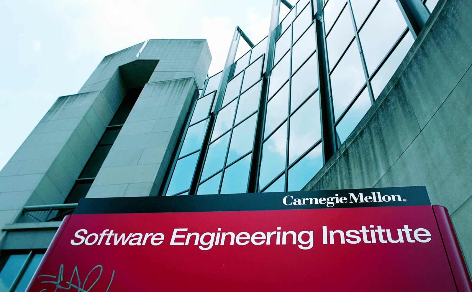 A red sign reading "Software Engineering Institute" stands in front of a building edifice that is full of glass windows