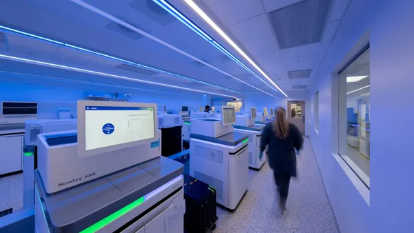 A scientist in blue clothing walks past sequencing machines in a Caris Life Sciences tissue laboratory.