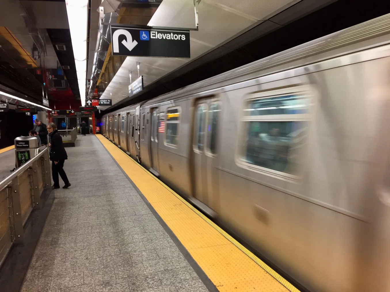 An aluminum New York City subway train at an underground station.