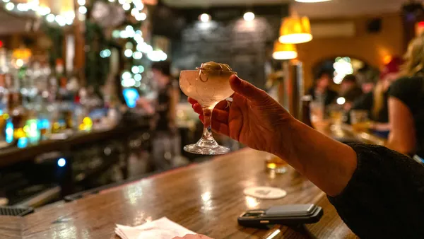 A cocktail is held at a bar.