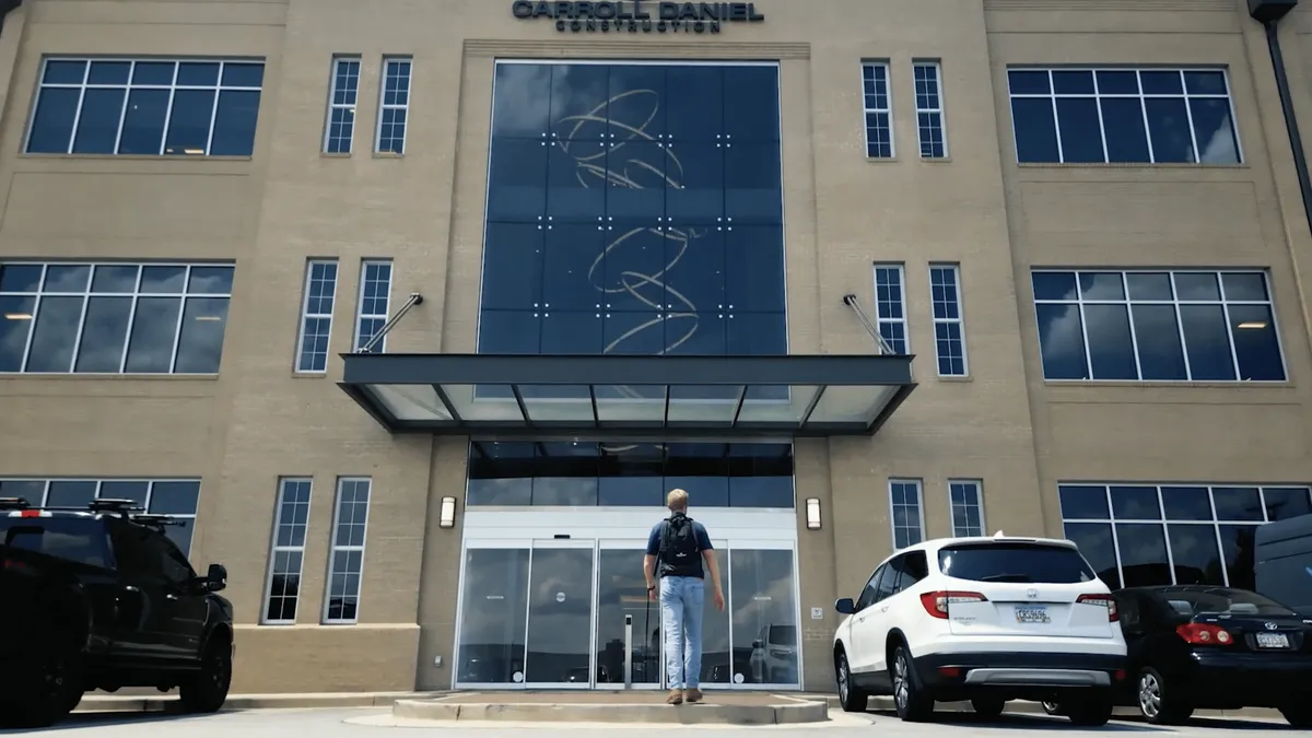 A worker with a backpack enters an office building