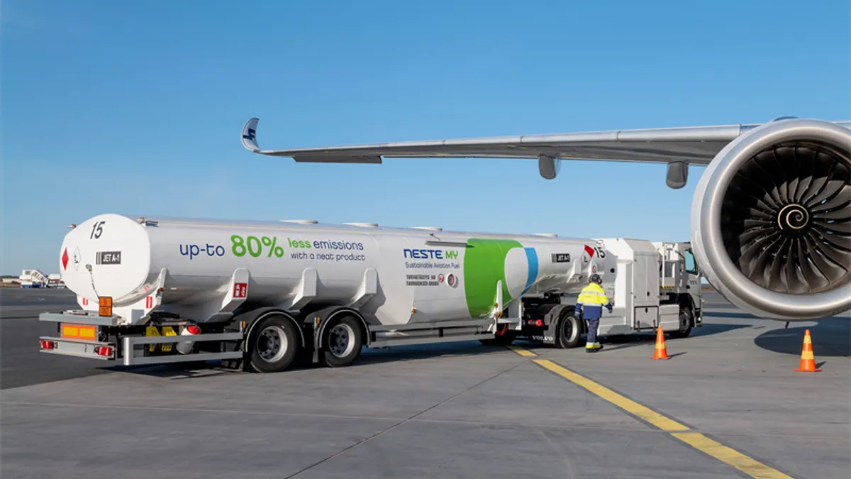 A truck full of NESTE SAF refuels an airplane sitting on a tarmac.