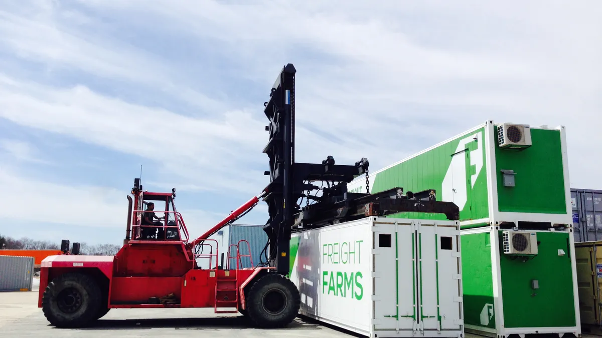 A forklift moves a shipping container with a logo reading Freight Farms