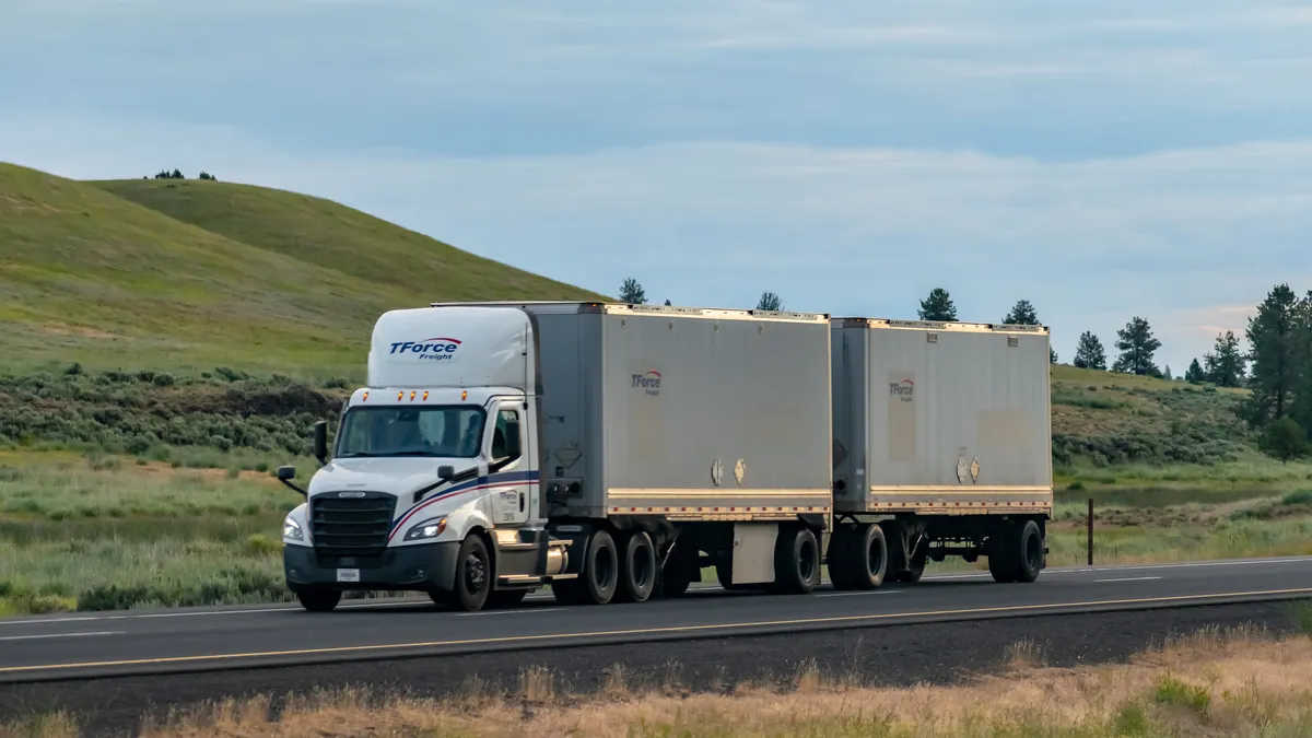 A TForce Freight double combination with a grassy hill and blue sky in the background.