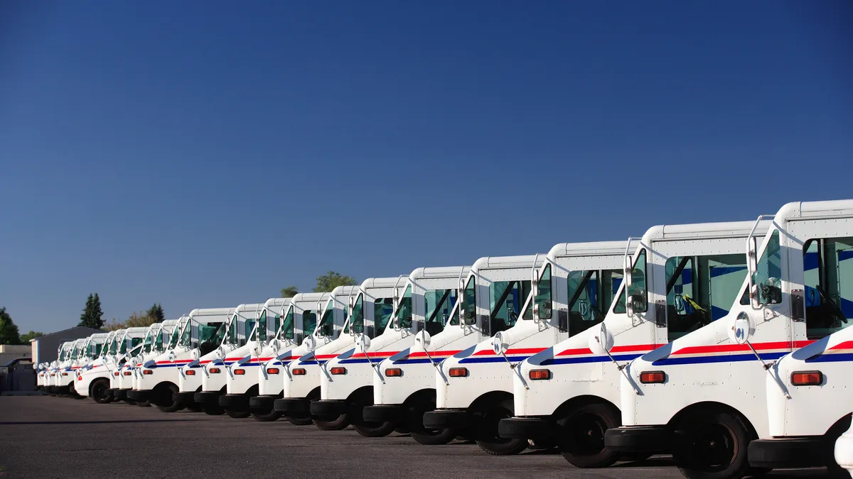 Postal Service trucks in a parking lot row.