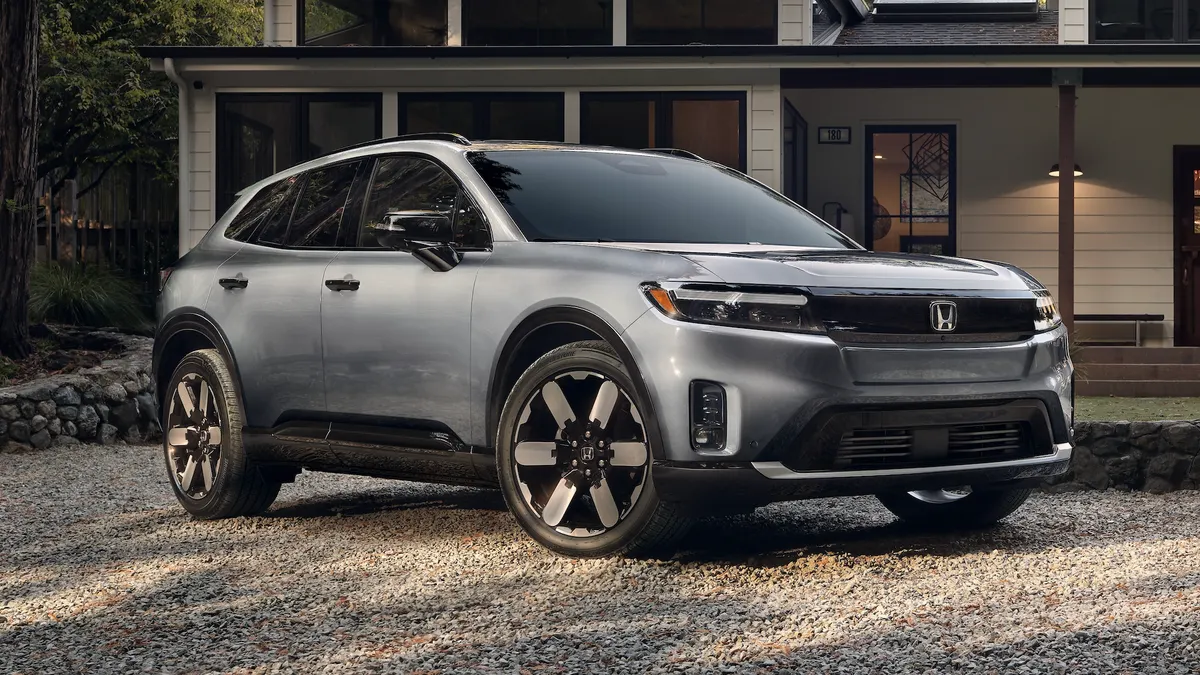 A 2024 Honda Prologue electric SUV parked in from of a house on a wooded lot.