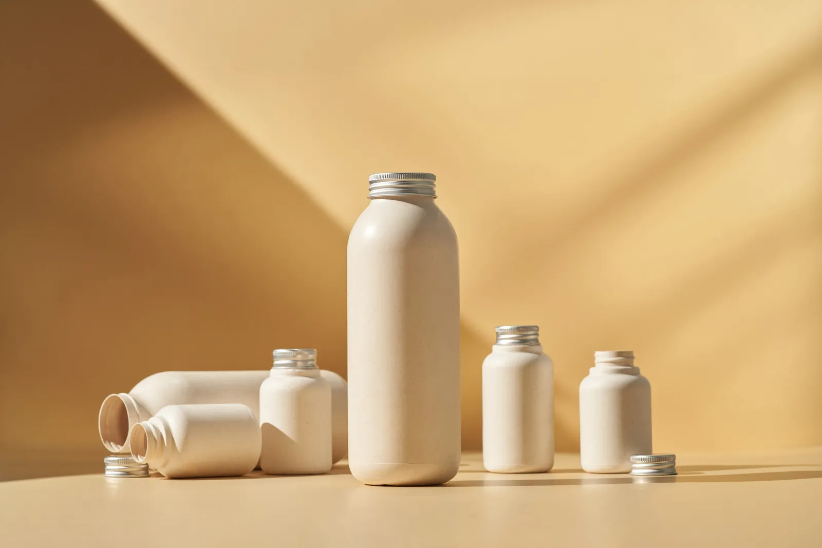 Six beige bottles of various sizes that are made from plant-based materials.