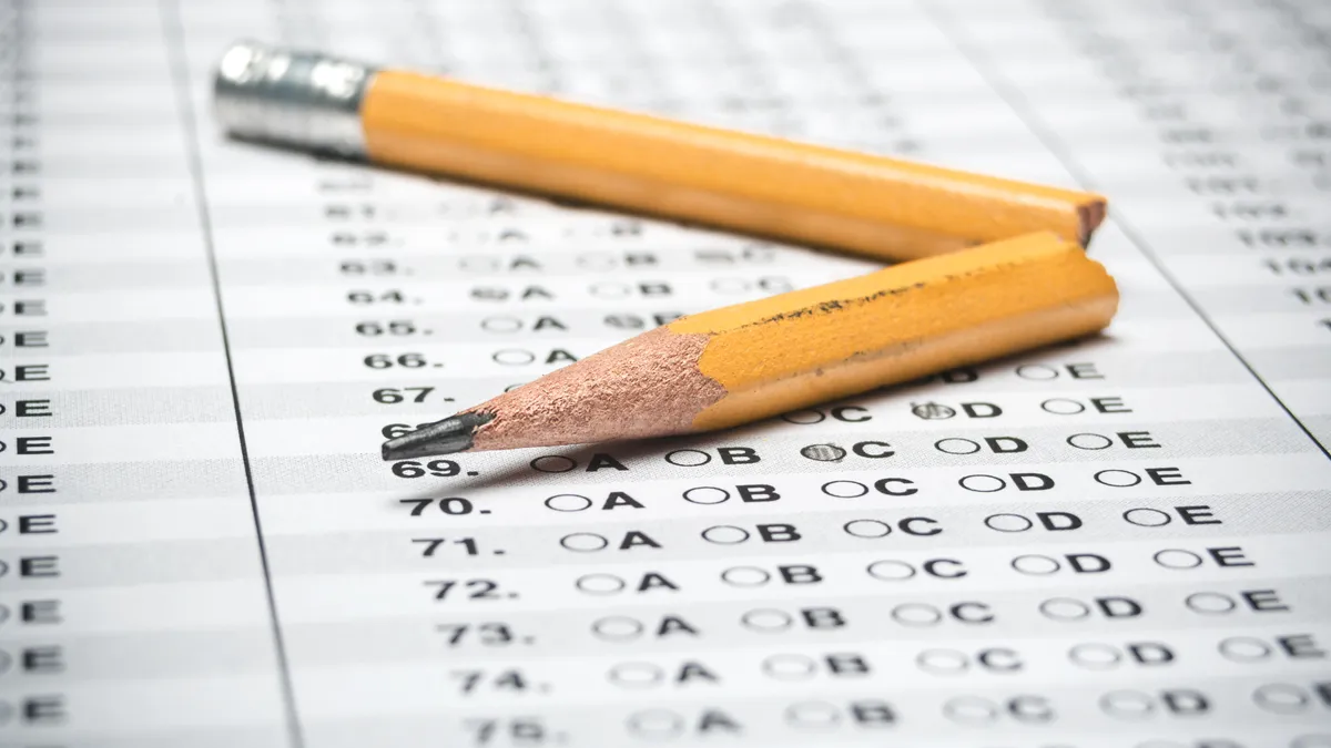 A snapped pencil sits on top of a blank multiple-choice testing sheet.