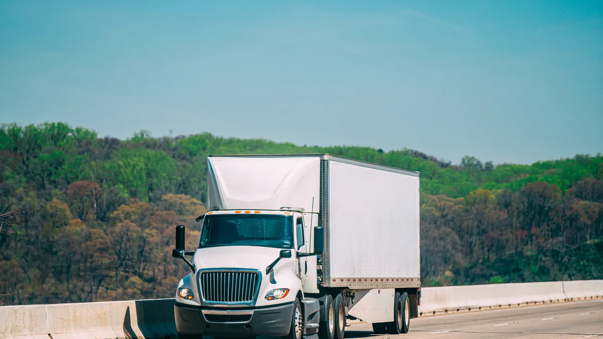 A white truck crosses a bridge alone.