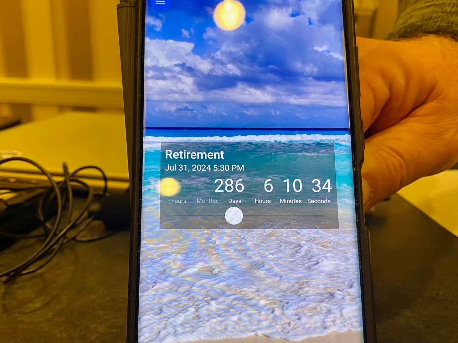 a photo of a smartphone screen with a retirement app showing a countdown to the days of retirement with a beach scene in the background