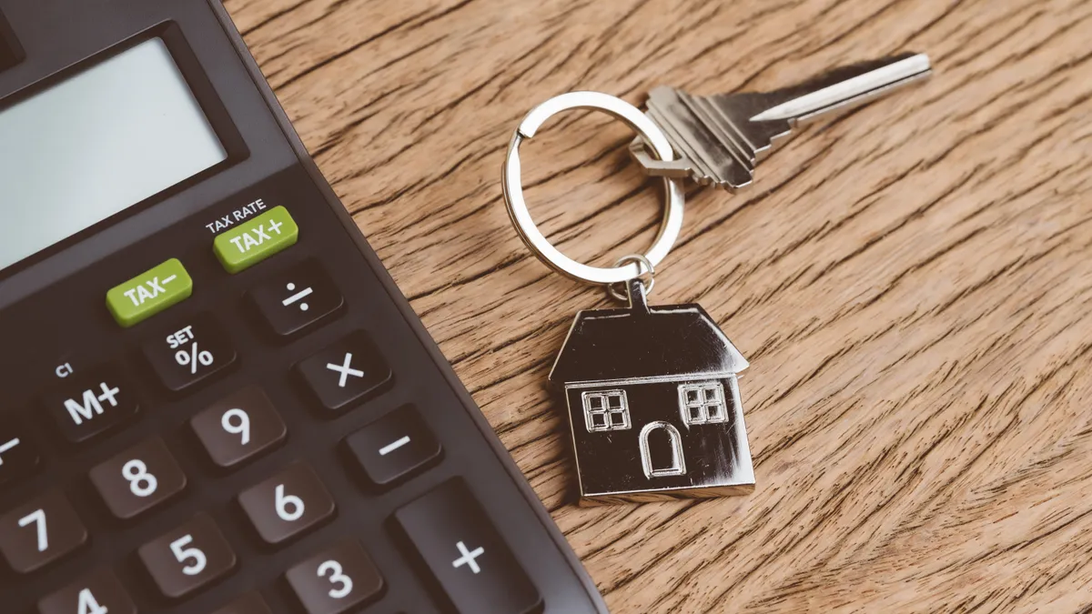 Home key with keychain with black calculator on wooden table