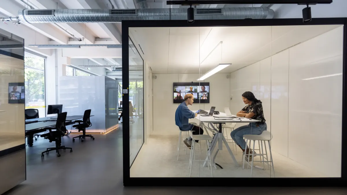 Two people talking to each other in a cubicle