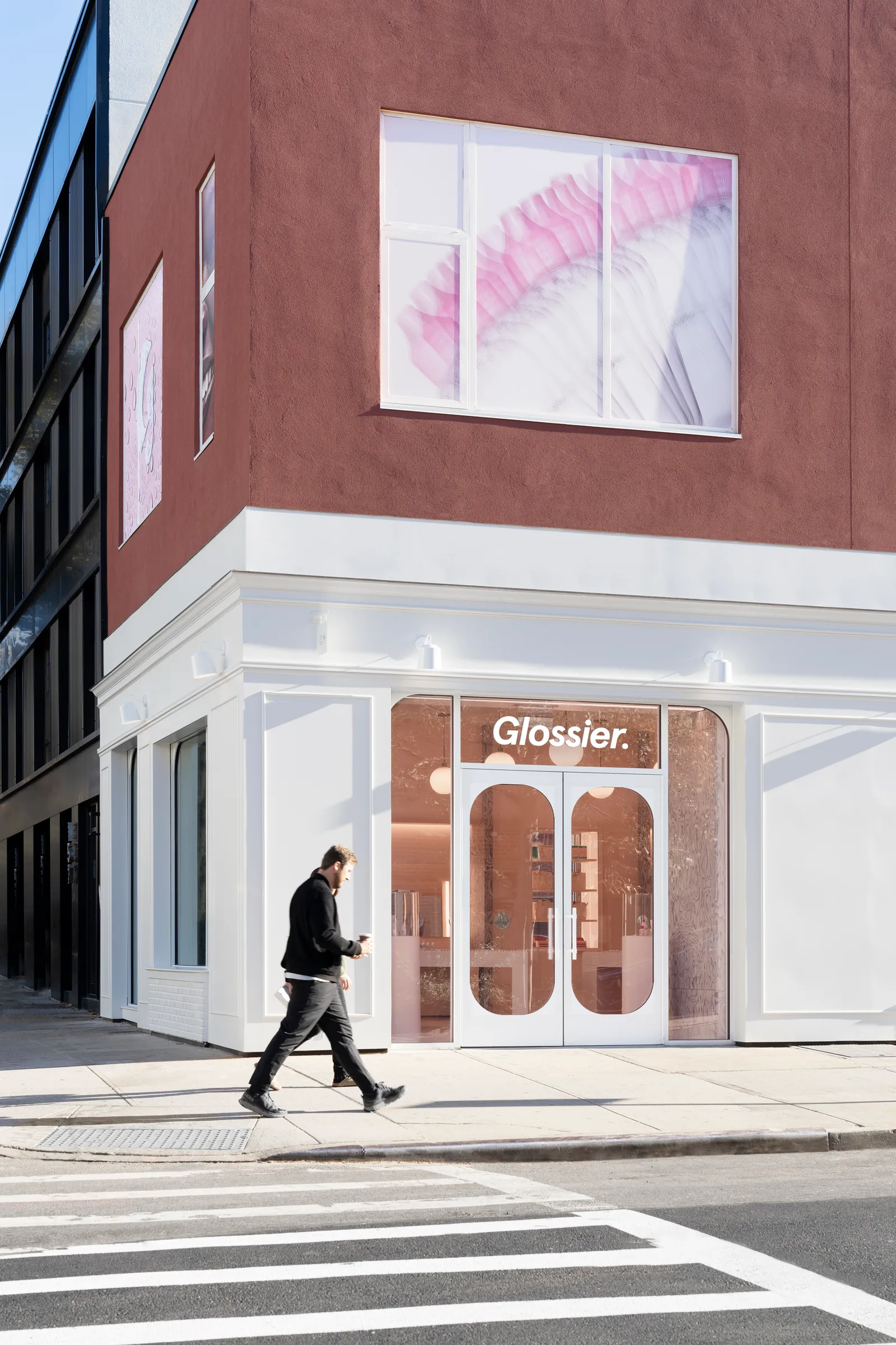 People walk by a white Glossier storefront in Brooklyn, New York.