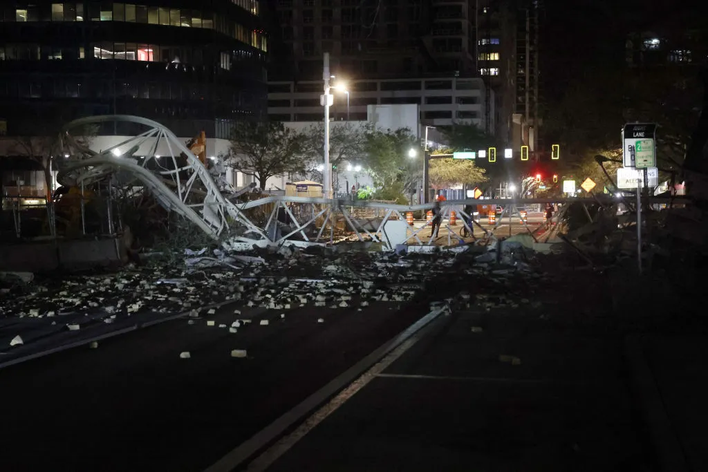 A collapsed tower crane lays across a dark road