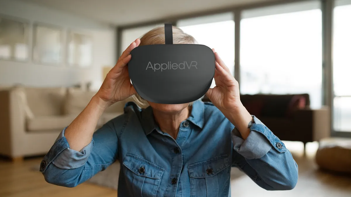 A person wears a black headset that says "AppliedVR" on the front