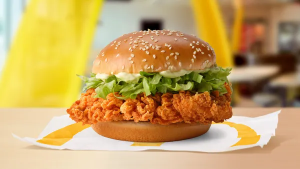 A close up photograph of a crispy chicken sandwich on a table within a McDonald's restaurant