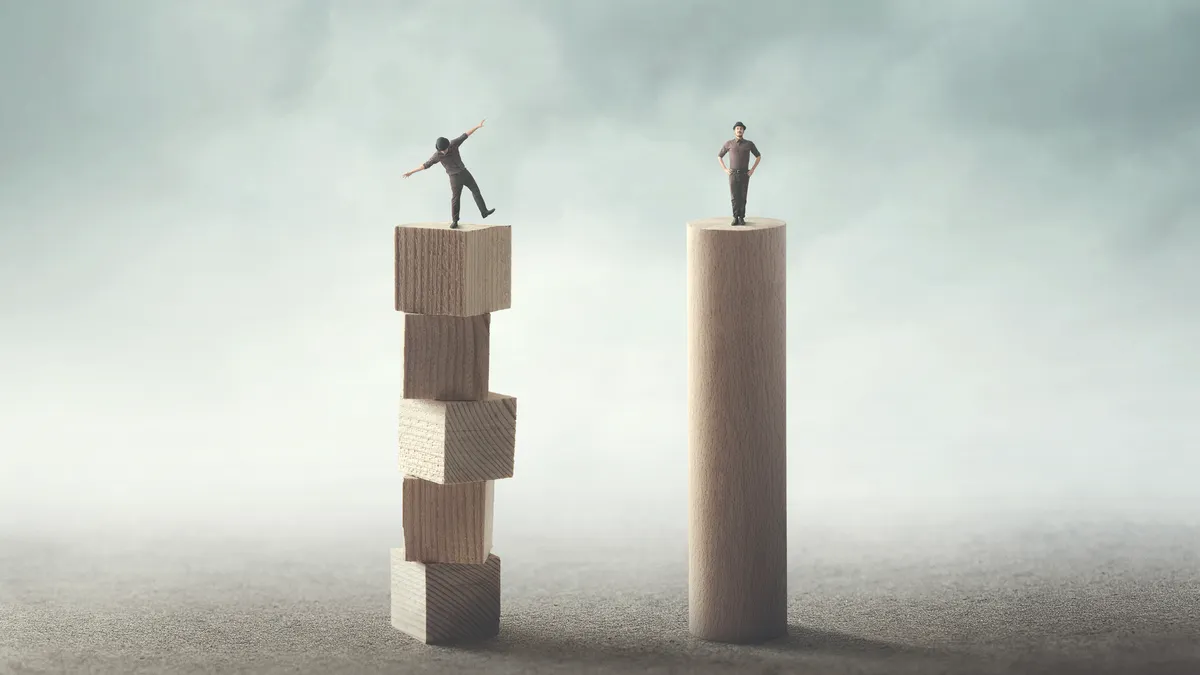 an illustration of two men, one on top of a stable wooden pillar and the other trying to balance atop several jenga-like blocks that are instable