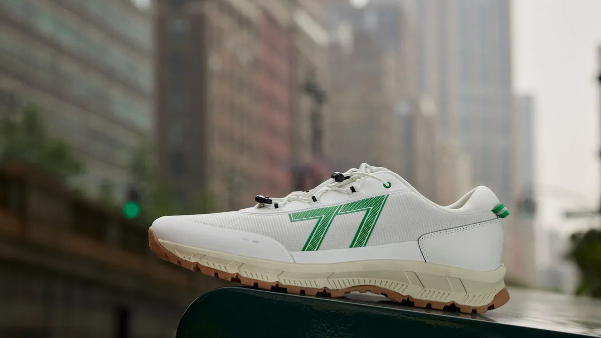 Green and white Le Tigre sneaker sits in the foreground of a New York City building shot