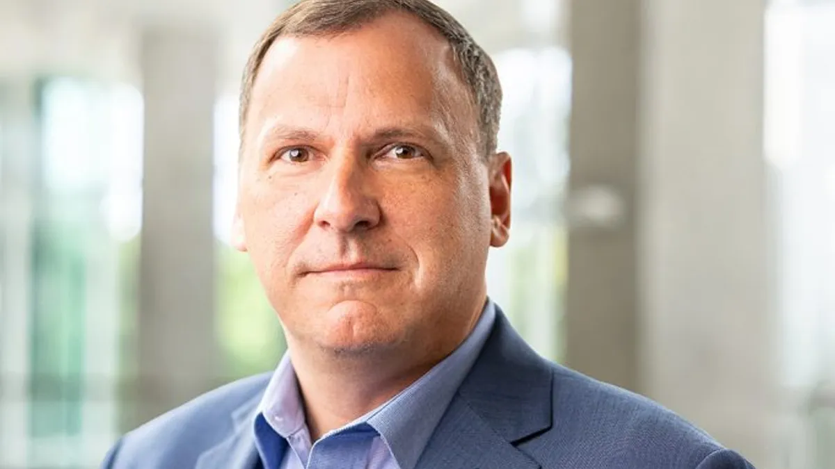 A portrait of REV Groups CEO and President Mark Skonieczny in a gray-blue blazer and a light blue shirt.