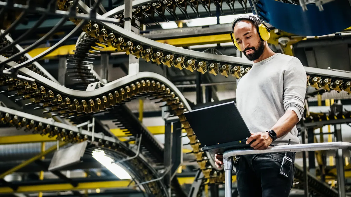 A print factory engineer standing alongside a variety of moving rails and machinery.