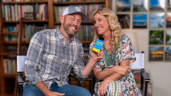 Jenny and Dave Marrs sitting on chairs. Dave is holding a box of Aleve.