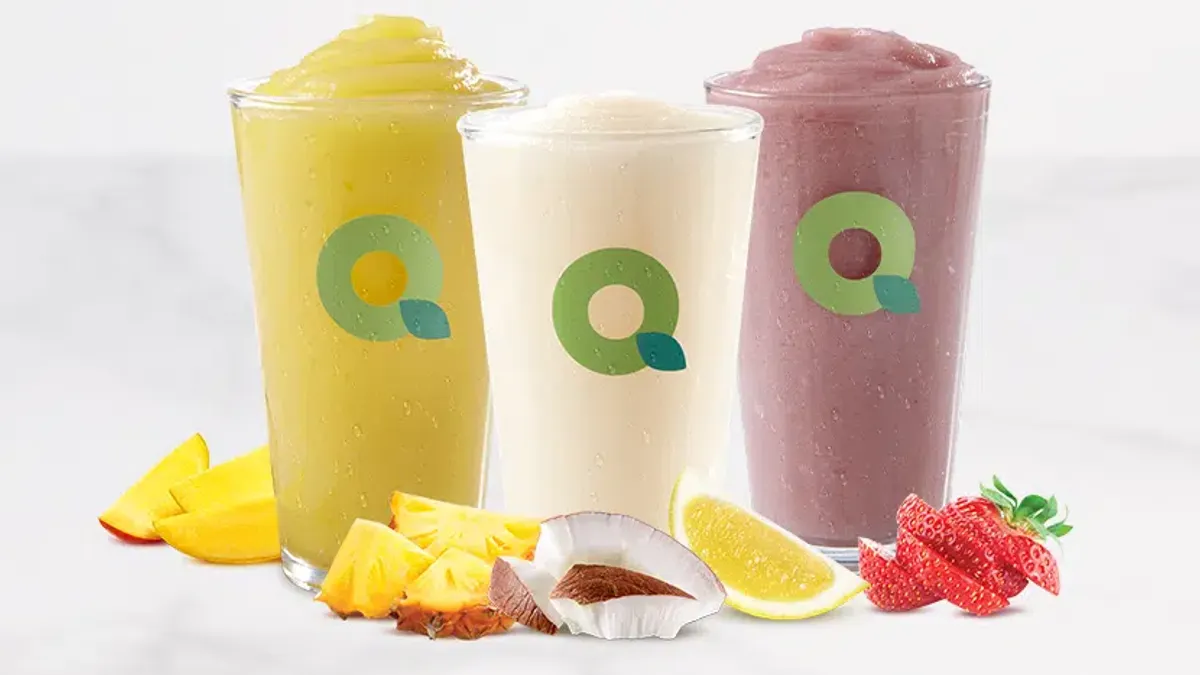 A photo of several beverages in see-through glasses. The glasses have a green Q on them.