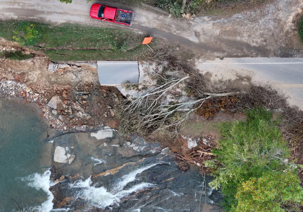 Aerial image shows a road washed out with a tree fallen across it.