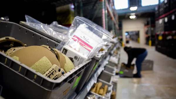 Tan helmets sit in a gray plastic container on a shelf.