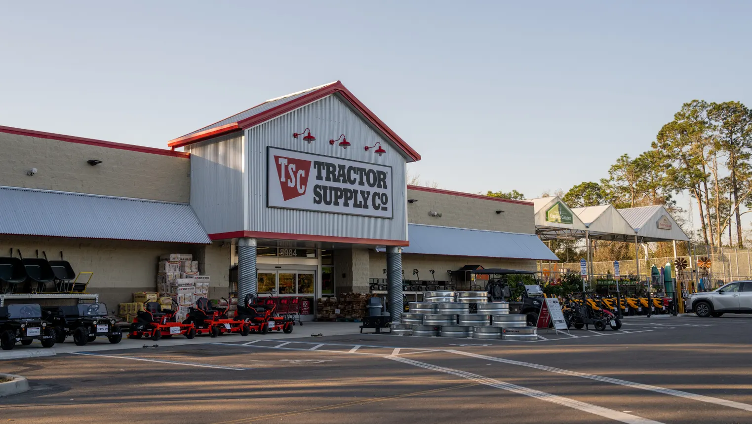 A storefront with riding mowers, wheelbarrows and other garden equipment out front.