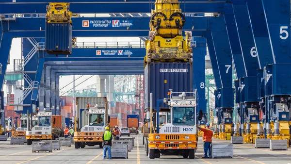 Dockworkers move cargo on a container terminal.