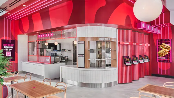 A bright pink restaurant interior with big digital display signs.