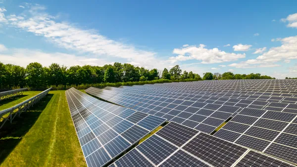 Rows of sustainable energy solar panels set up on farmland.