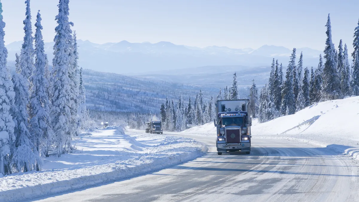 Trucks drive along a snowy highway in Alaska.