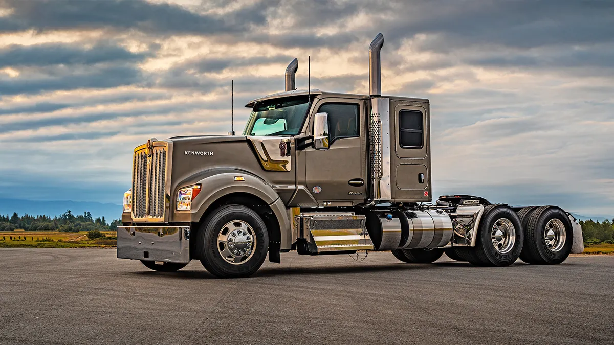 A freight truck parked on a paved road with a nice cloudy backdrop.