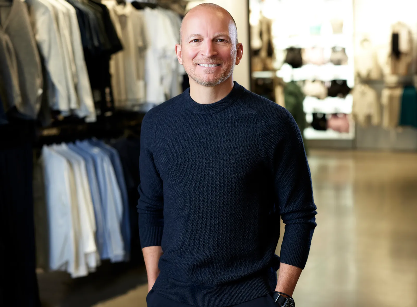 A shot of JJ Collier, Lululemon&#x27;s vice president of design for outerwear, in a blue sweater in front of a clothing display.