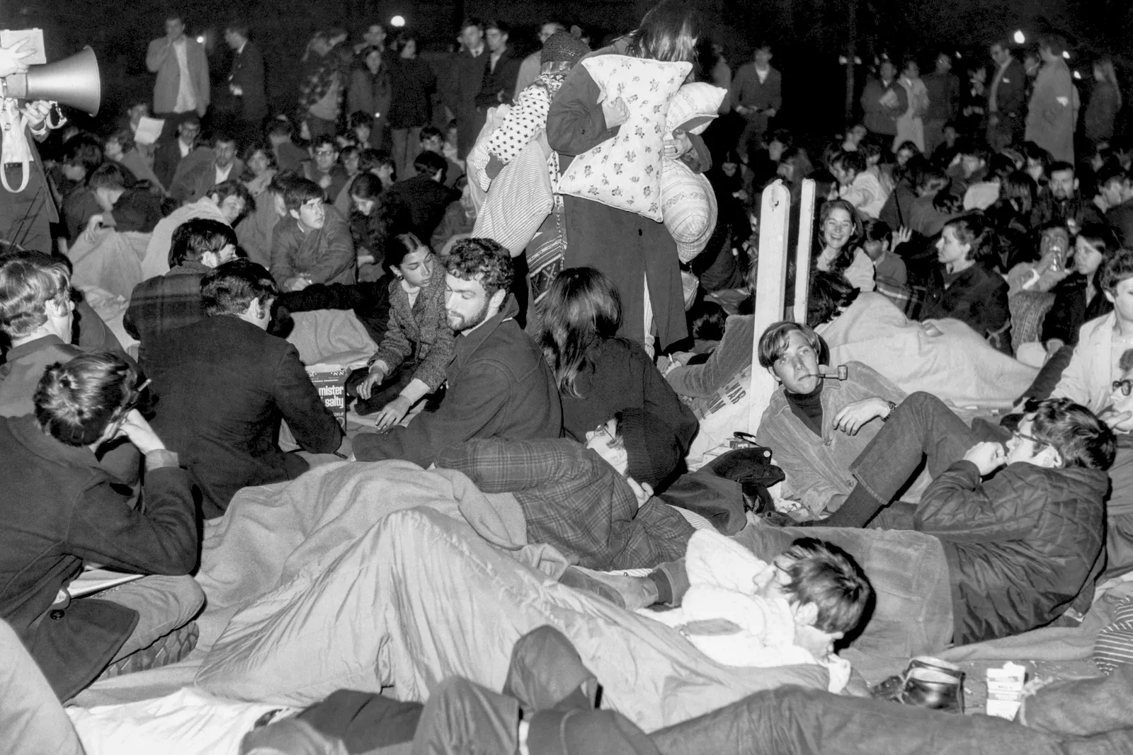 A group of protesters sit with pillows and blankets.