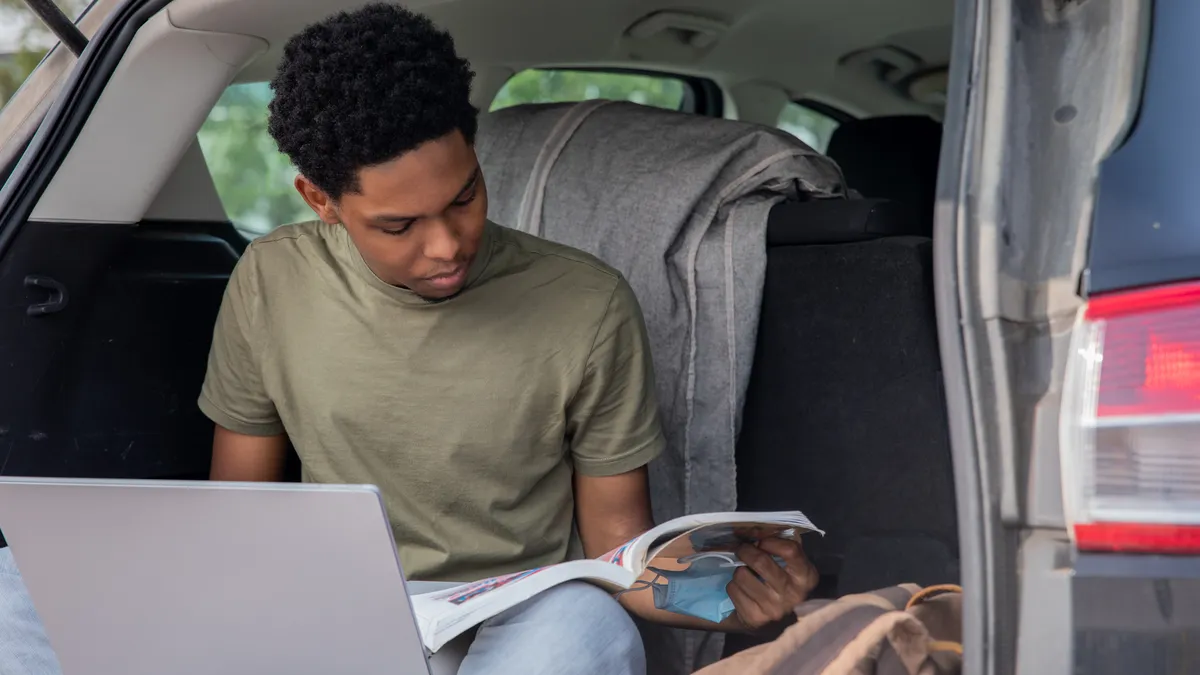 A homeless student studies in the trunk of his car