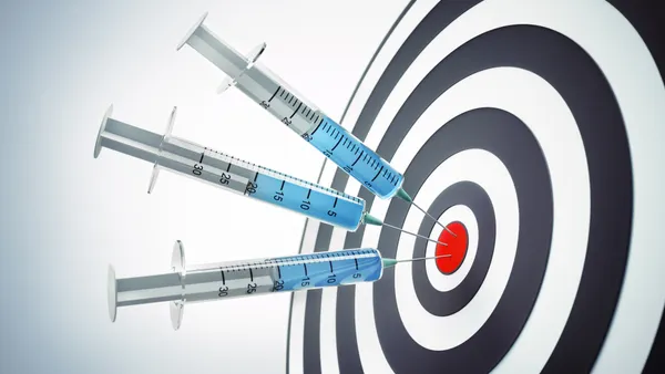 Syringes embedded in a dartboard around the bullseye.