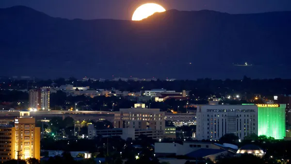 a moon atop a city skyline