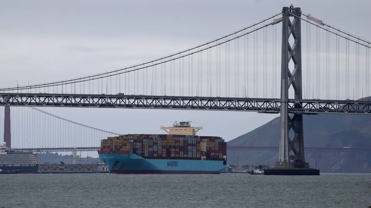 A large container ship passes under the San Francisco – Oakland Bay Bridge