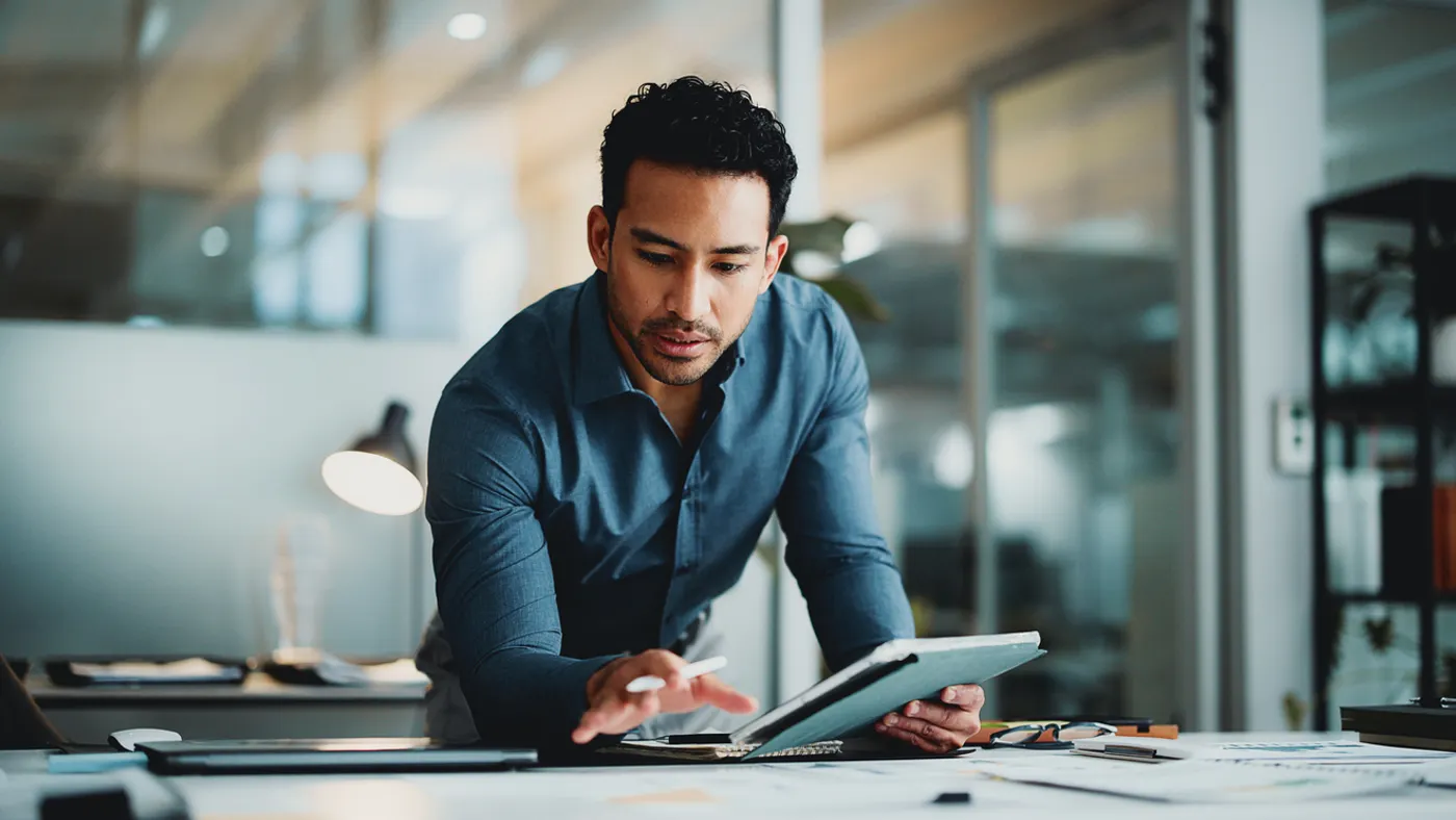 Man leaning over a table with a tablet in his hand planning