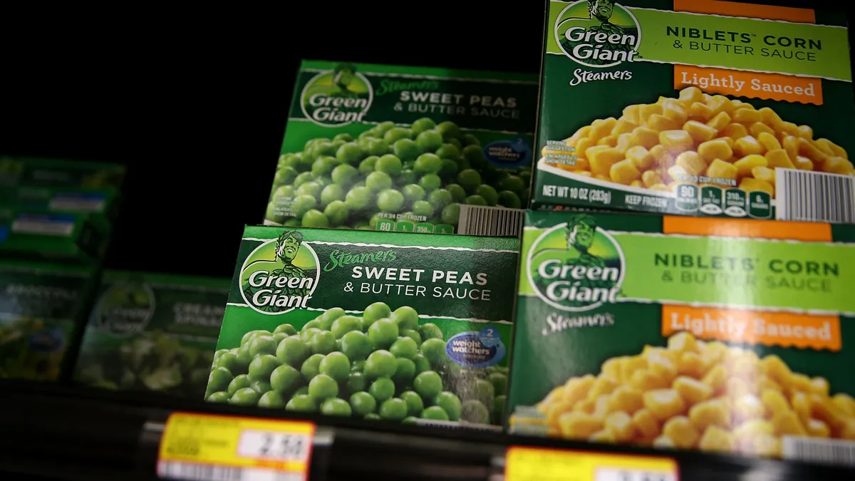 Packages of Green Giant frozen peas and corn are displayed at a supermarket.