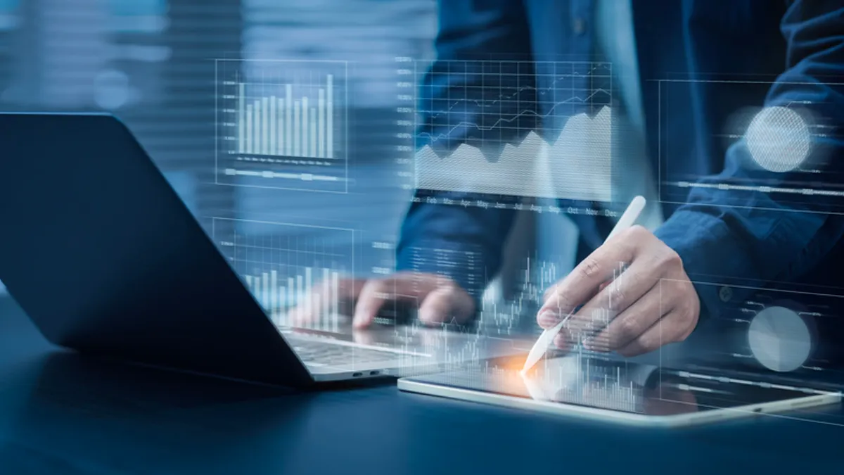 Image of a business person's hand and blue image of screen with financial graphics.