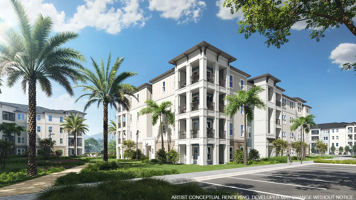 Four-story apartment community with palm trees in the foreground.