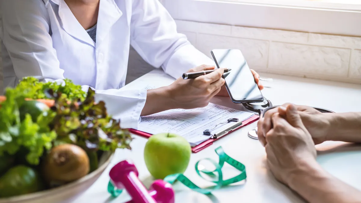 Nutritionist giving consultation to patient with fruits and vegetables