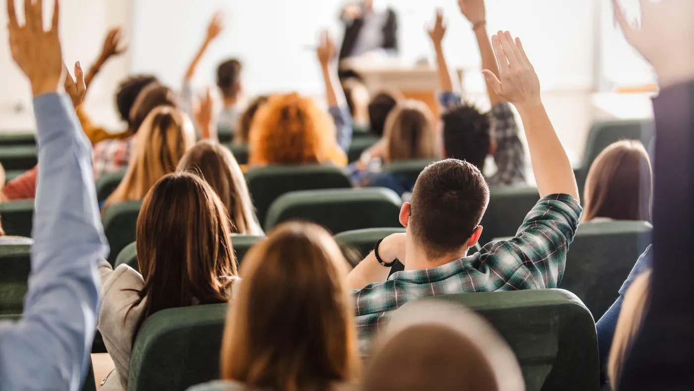 A professor speaks to a lecture hall of college students.